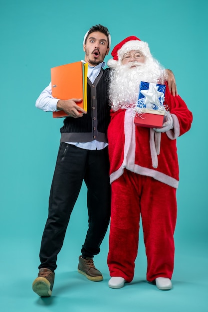 Vista frontale di babbo natale con il giovane e regali sulla parete blu