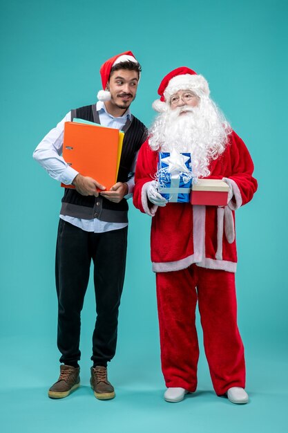 파란색 벽에 젊은 남자와 선물 산타 클로스의 전면보기