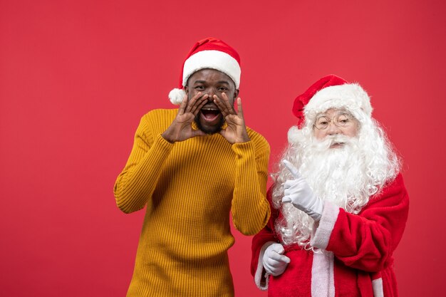 Front view of santa claus with young man on red wall