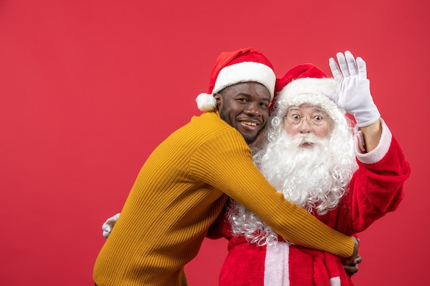 Front view of santa claus with young man on red wall