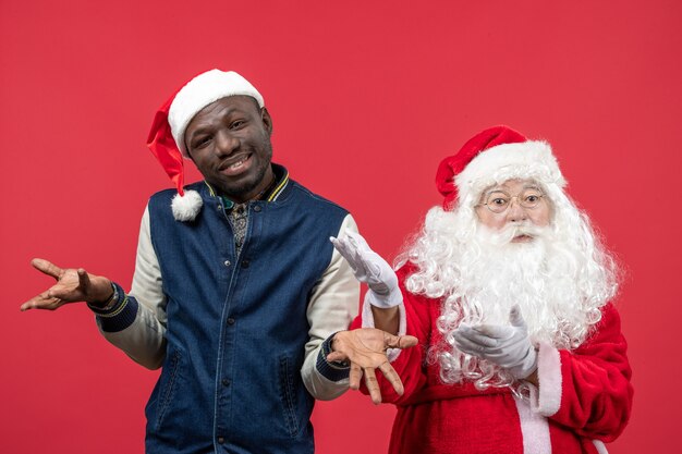 Front view of santa claus with young man on red wall