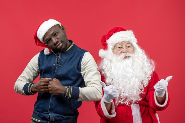 Front view of santa claus with young man on red wall