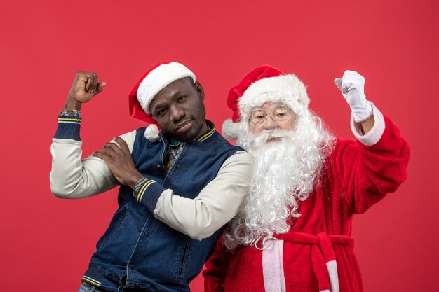 Front view of santa claus with young man on red wall