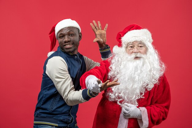 Front view of santa claus with young man on the red wall