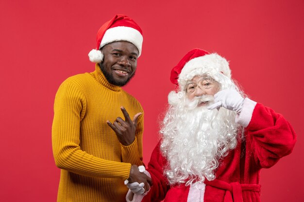 Front view of santa claus with young man on the red wall