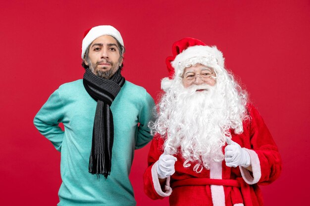 Front view of santa claus with young man standing on red wall