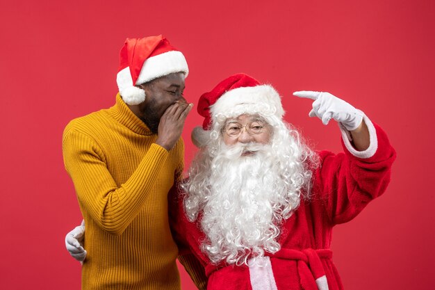 Front view of santa claus with young young man on a red wall