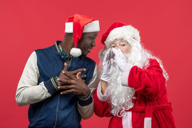 Front view of santa claus with young young man on a red wall