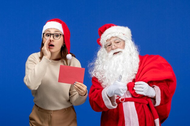 Вид спереди санта-клауса и молодой женщины, держащей письмо на синем празднике, рождество, новый год, цветная эмоция