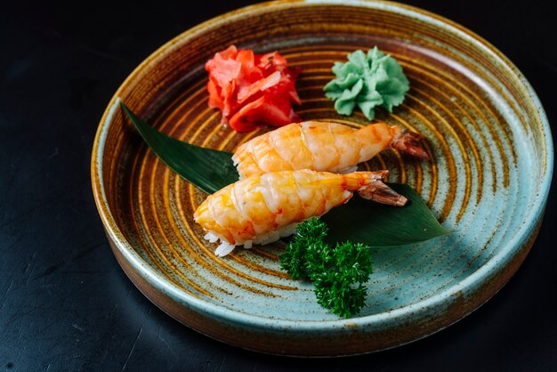 Front view sashimi sushi with shrimp with wasabi and ginger on a plate