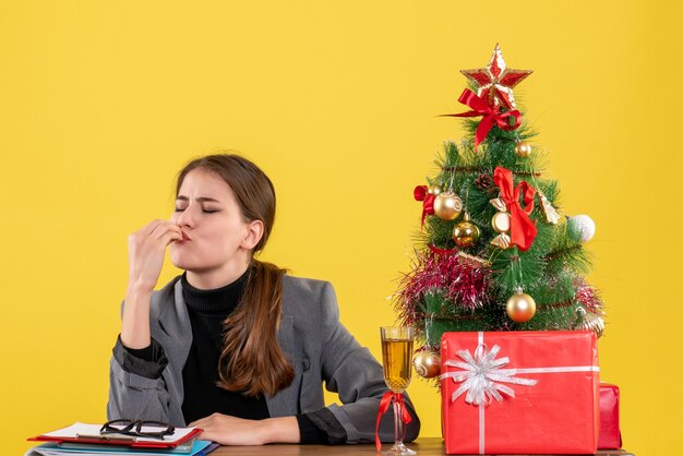 正面図は、クリスマスツリーとギフトカクテルの近くにチーフのキスサインを作る机に座って満足している女の子