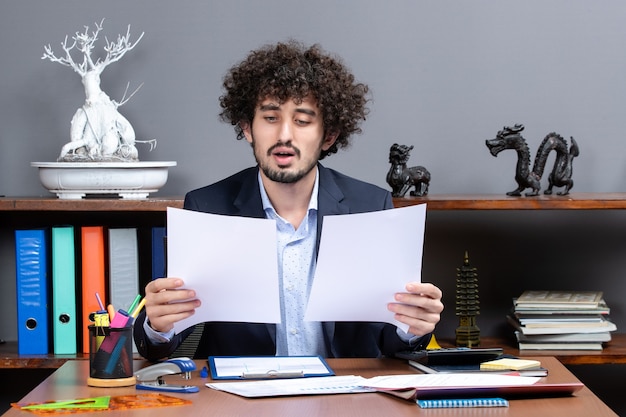 Front view of satisfied young businessman working in office