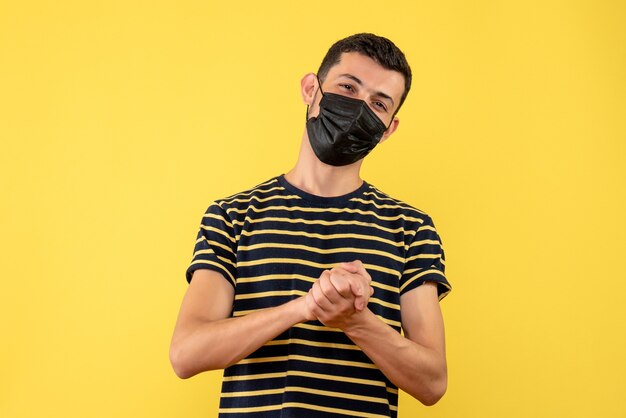 Front view satisfied young man in black and white striped t-shirt yellow isolated background