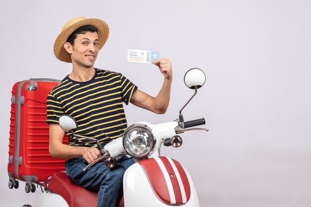 Front view of satisfied young man with straw hat on moped holding air ticket