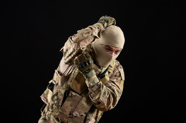 Front view scared young soldier in uniform on black wall