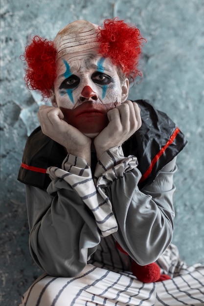 Free photo front view scary clown in abandoned building