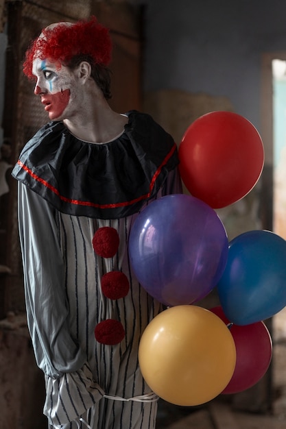 Free photo front view scary clown in abandoned building