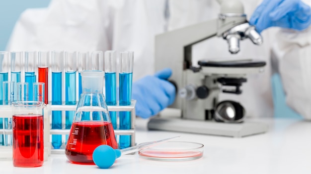 Free photo front view scientist checking a substance with a microscope