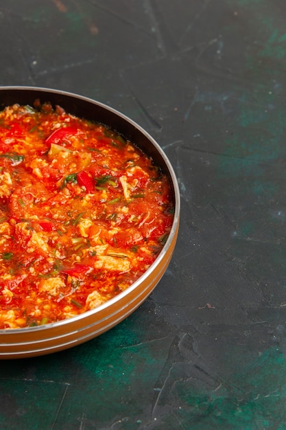 Front view scrambled eggs with tomatoes and greens inside pan on the dark green surface