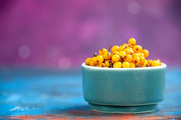 Front view sea buckthorn in bowl on blue table pink isolated table with copy space