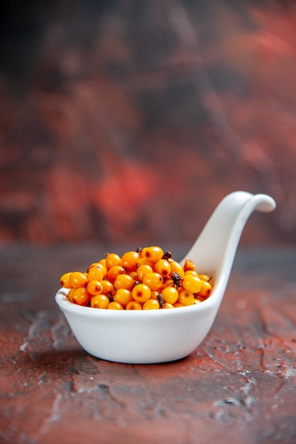 Front view sea buckthorn in white bowl on dark red isolated surface copy place