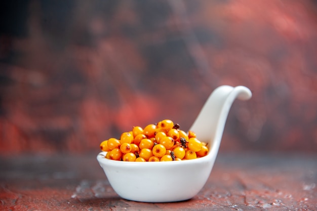 Front view sea buckthorn in white bowl on dark red isolated surface copy space