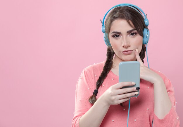 front view of seductive woman wearing headphones and holding smartphone