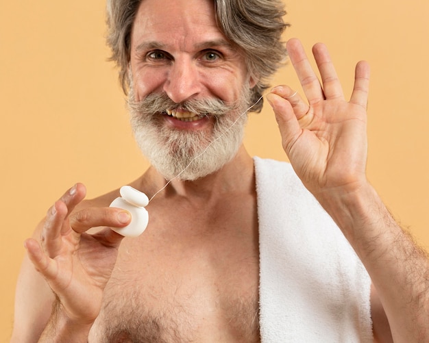 Free photo front view of senior bearded man with dental floss