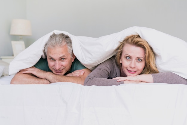 Coppie senior di vista frontale a letto che esaminano macchina fotografica