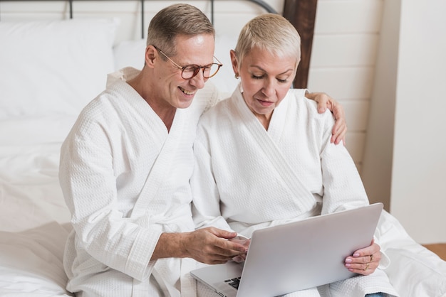 Front view senior couple looking on a laptop in bed