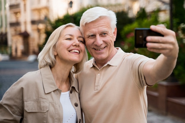 Front view of senior couple taking a selfie while out in the city