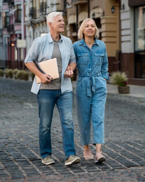 街を散歩しているタブレットで年配のカップルの正面図
