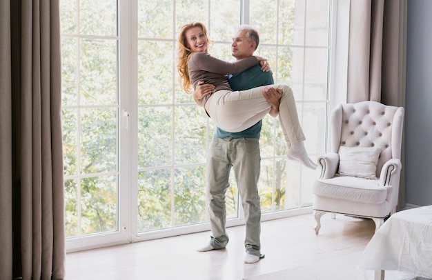 Front view senior man carrying woman indoors