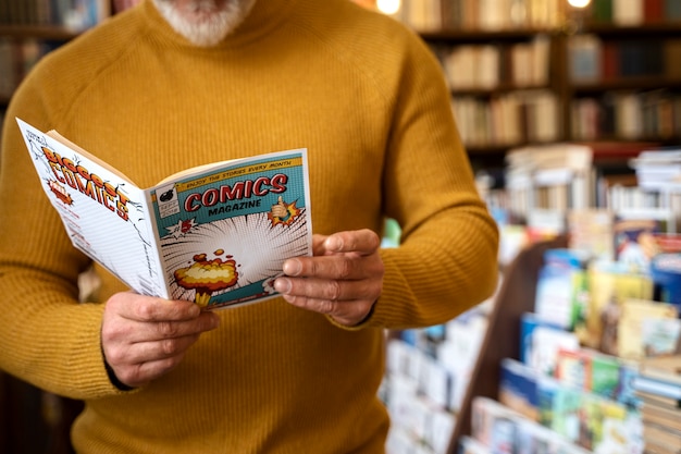 Foto gratuita fumetti della lettura dell'uomo senior di vista frontale