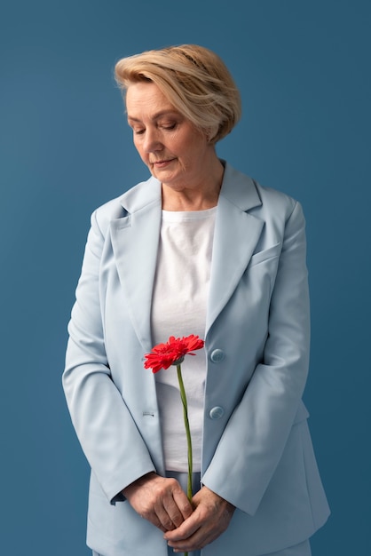 Free photo front view senior woman holding flower