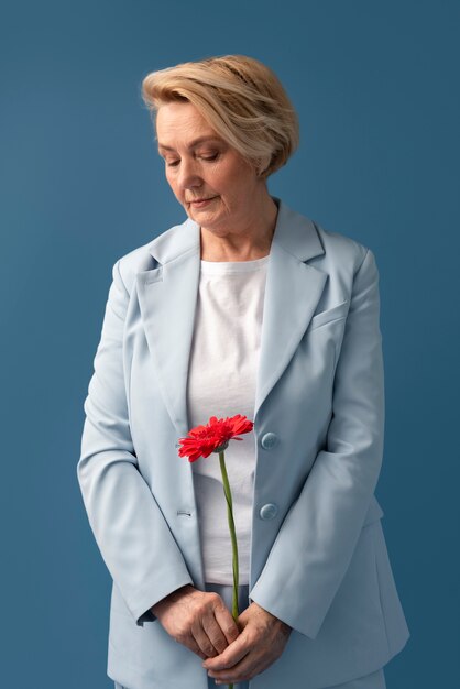 Front view senior woman holding flower