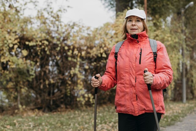 Front view of senior woman trekking outdoors with copy space