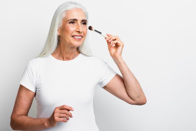 Front view senior woman with makeup brush