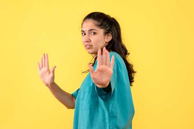 Front view serious pretty female doctor trying to stop something on yellow background