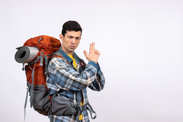 Front view serious traveler man with backpack making finger gun