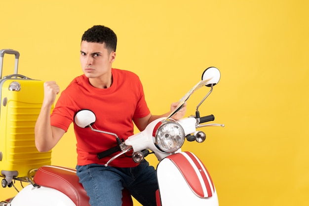 Front view serious young man on moped showing punch