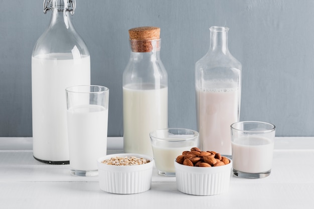 Vista frontale set di bottiglie di latte e bicchieri con farina d'avena e mandorle