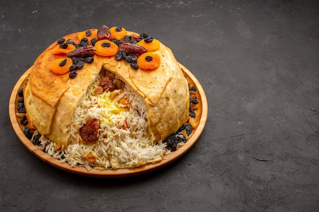 Free photo front view shakh plov delicious rice meal cooked inside round dough with raisins on grey space