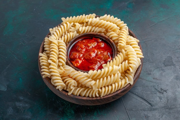 Front view shaped italian pasta with tomato sauce on dark-blue surface