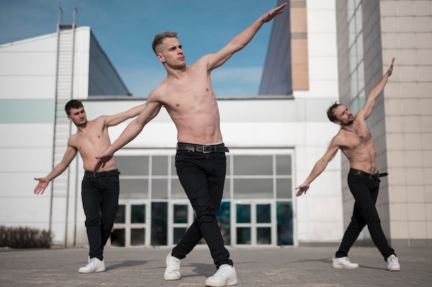 Front view of shirtless hip hop dancers rehearsing outside