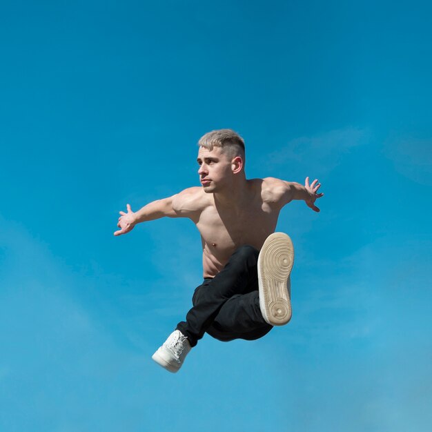 Front view of shirtless hip hop performer pose mid-air