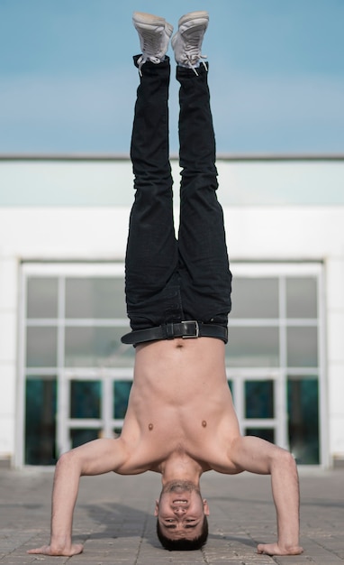 Free photo front view of shirtless hip hop performer standing on his head