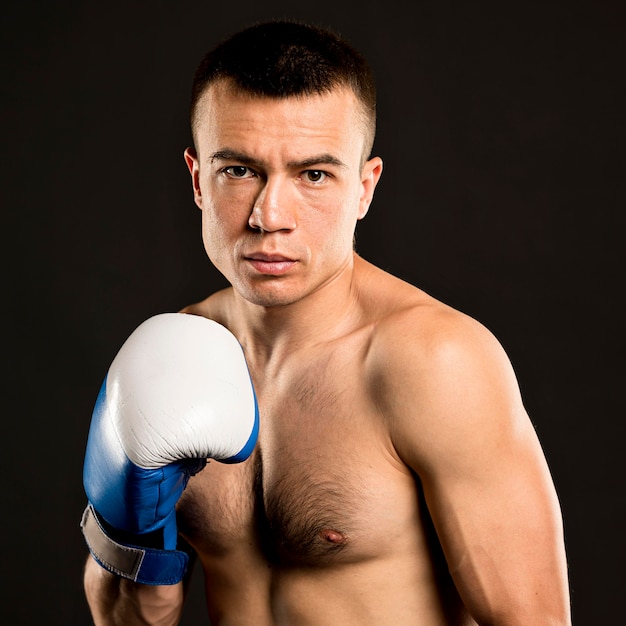 Free photo front view of shirtless male boxer with protective glove