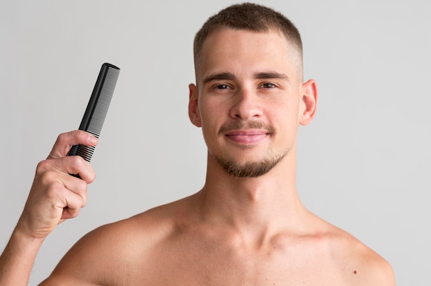 Front view of shirtless man holding a comb