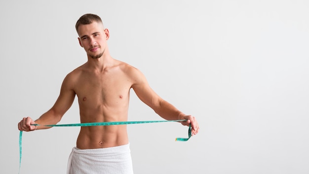 Free photo front view of shirtless man holding measuring tape with copy space